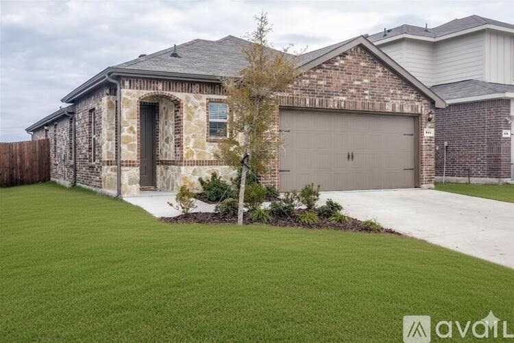 A house with a garage and a tree in front of it.