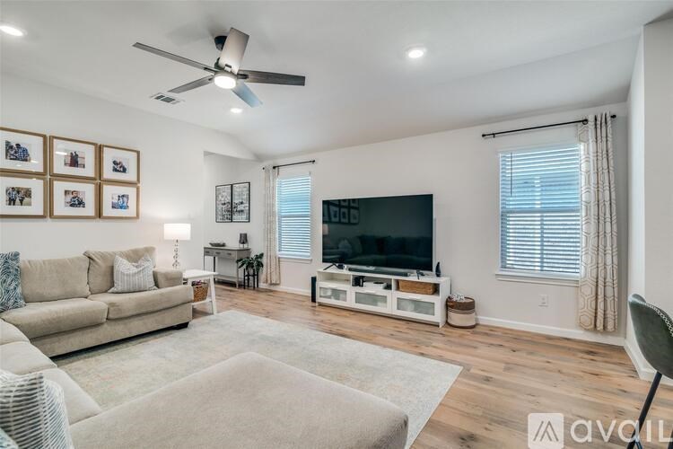 A living room with a beige sofa, a television, and a rug.