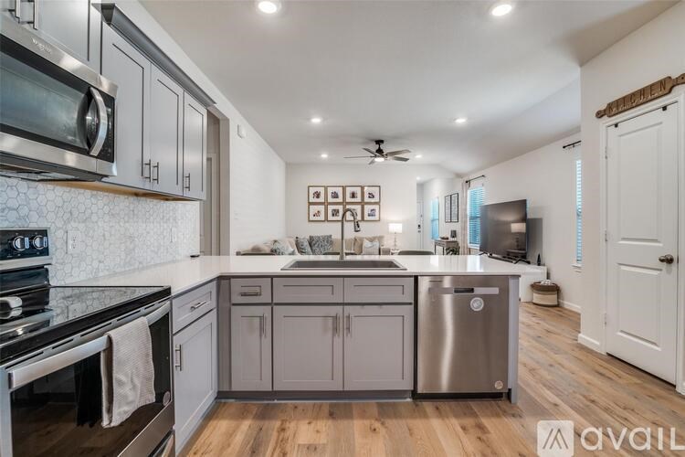 A modern kitchen with stainless steel appliances and wooden floors.