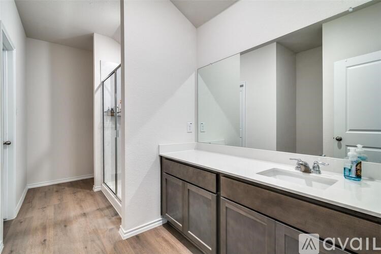 A bathroom with a sink, mirror, and a shower.