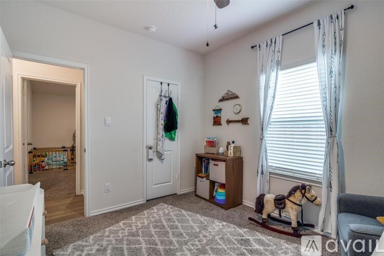 A room with a rocking horse and a grey rug.