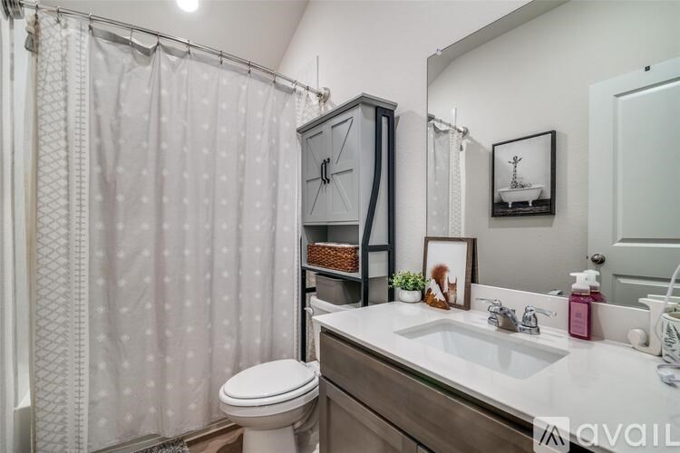 A bathroom with a white toilet, a sink, a mirror, and a shower curtain.