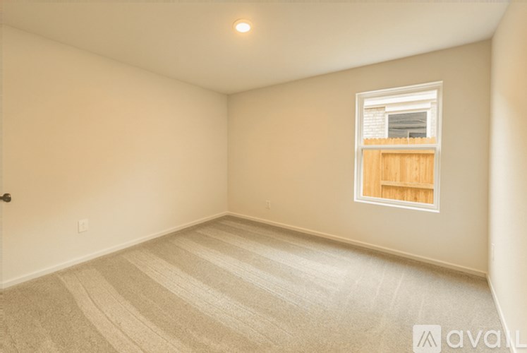 A room with a carpeted floor and a window with wooden blinds.