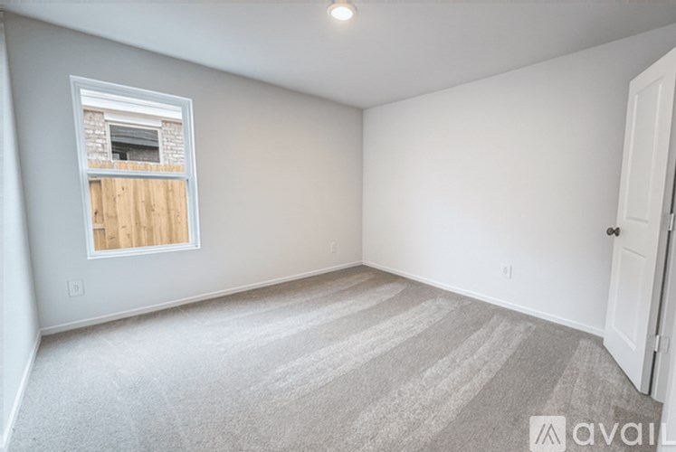 A room with a carpeted floor and a window with wooden panes.