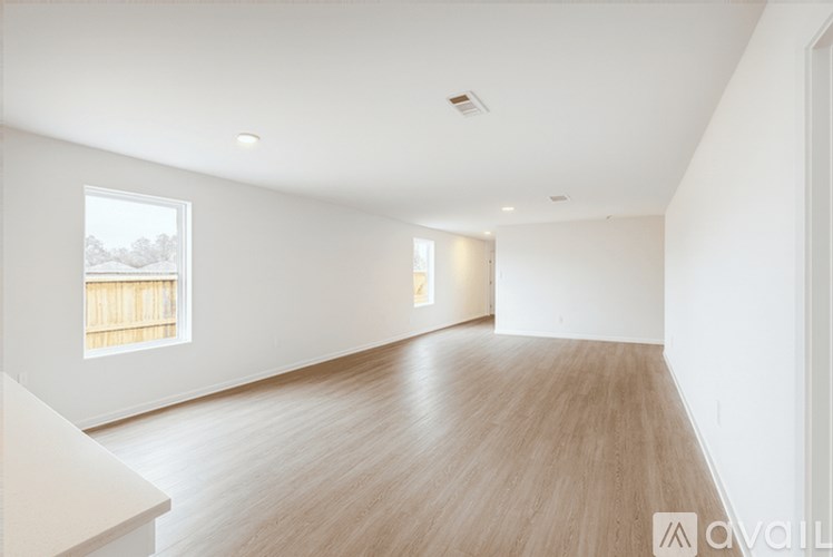 A spacious room with wooden flooring and a window overlooking a snowy landscape.