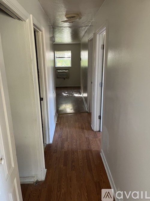 A long hallway with wood floors and white walls.
