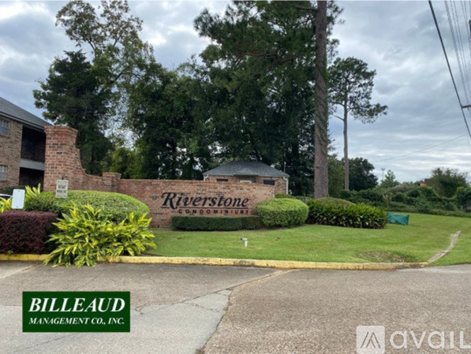 A sign for Riverstone Condominiums is displayed in front of a building.