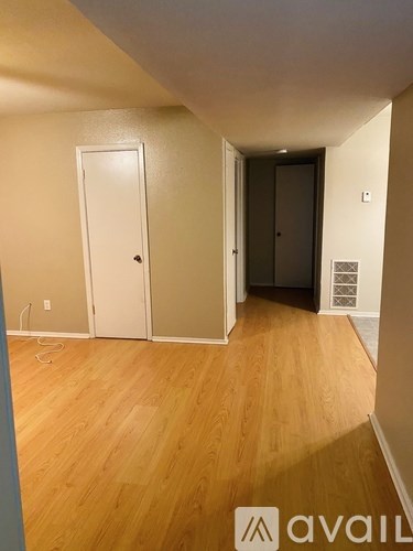 A room with wooden flooring and two doors, one of which is closed.