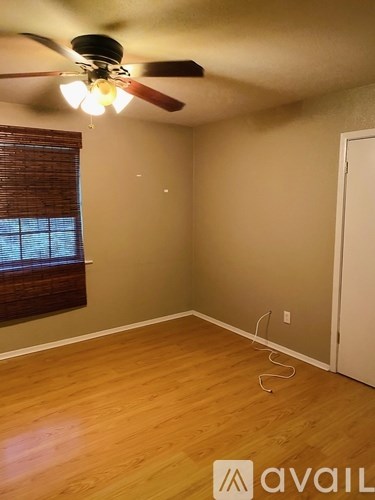 A room with a ceiling fan and a window with blinds.