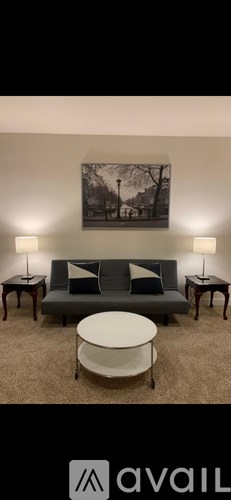 A living room with a grey couch, a white coffee table, and two lamps on either side of the couch.