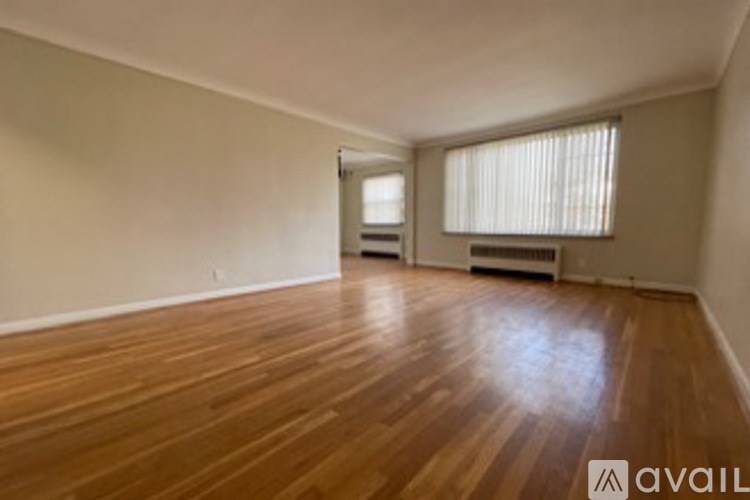 A room with wooden flooring and two windows.