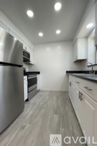 A modern kitchen with stainless steel appliances and wooden flooring.