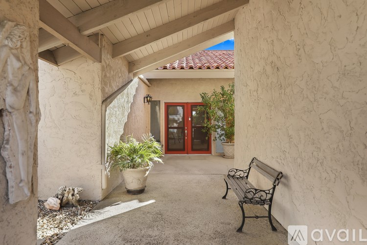 A patio with a bench and a potted plant.