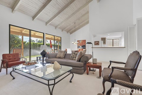 A living room with a glass coffee table and a grey couch.