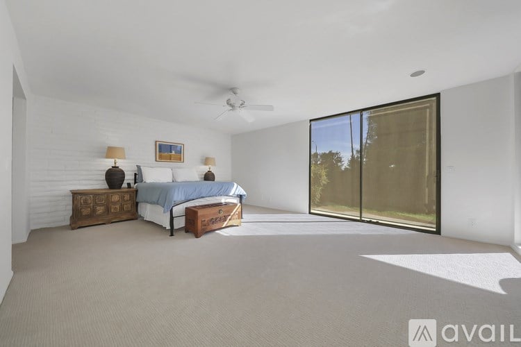 A bedroom with a bed, dresser, and sliding glass doors.