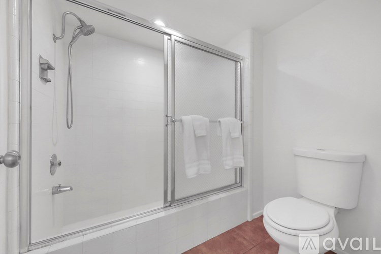 A white toilet sits next to a walk-in shower with a glass door.