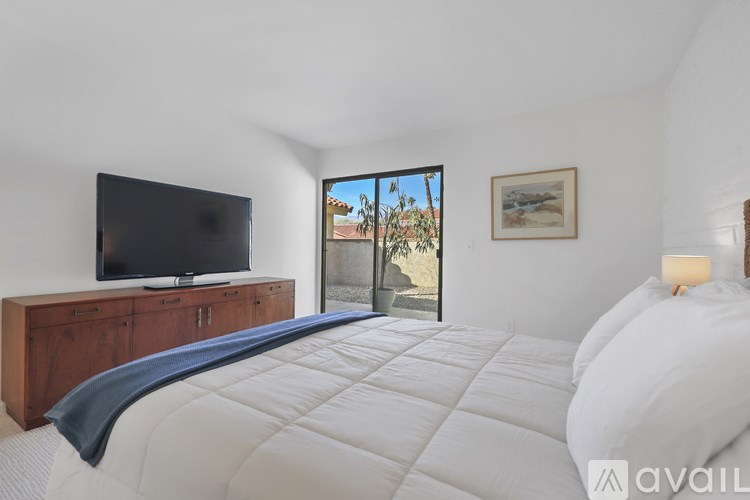 A bedroom with a large bed, a television, and a painting on the wall.