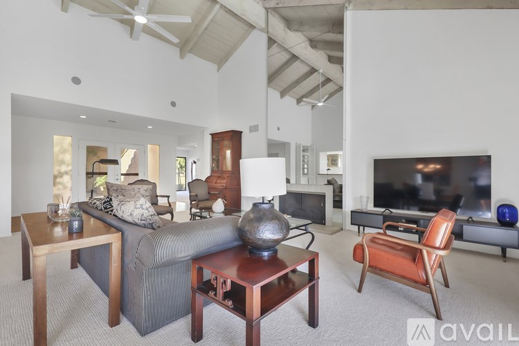 A living room with a grey couch, a wooden coffee table, and a television.