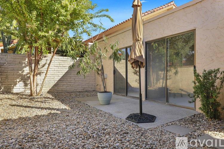 A patio area with a table and chairs and a hanging umbrella.