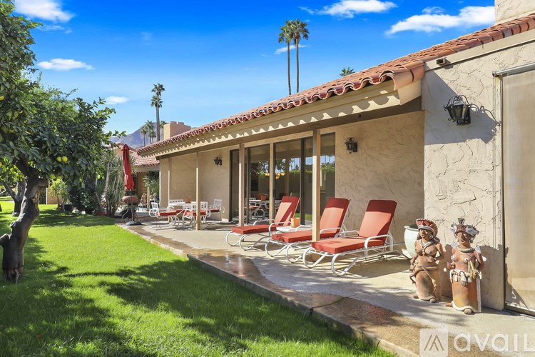 A house with a red tile roof and a patio with red chairs.