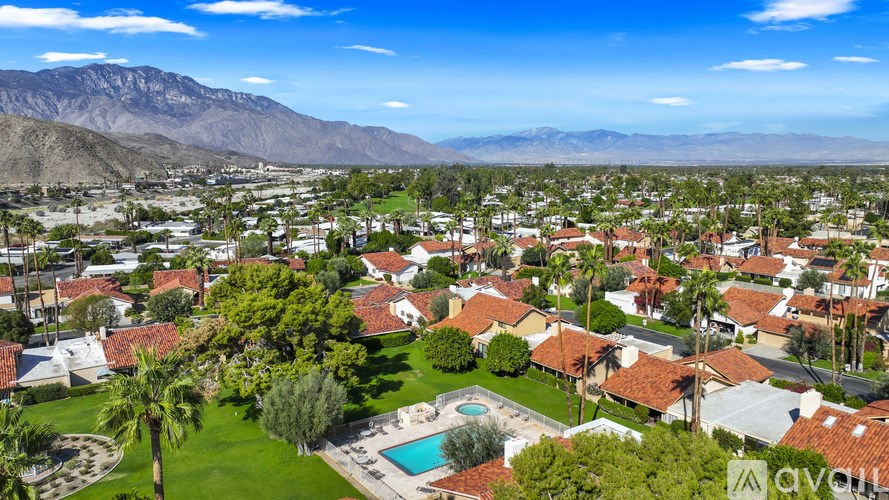 A bird's eye view of a residential area with houses, a pool, and palm trees.