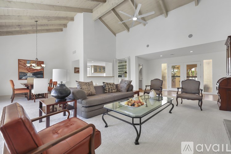 A living room with a glass coffee table and brown leather chairs.