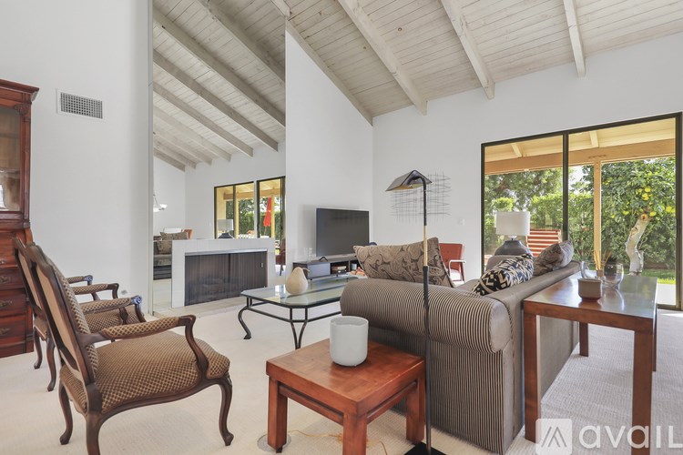 A living room with a couch, chairs, and a television.