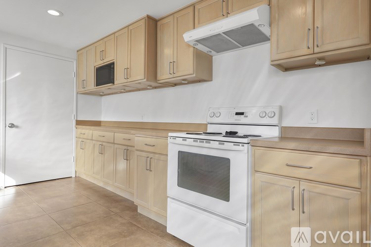 A kitchen with wooden cabinets and a white stove top oven.