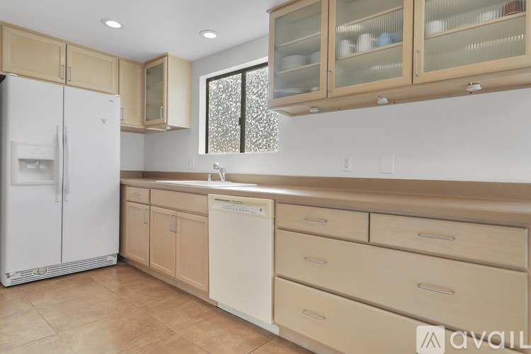 A kitchen with a white refrigerator and beige cabinets.