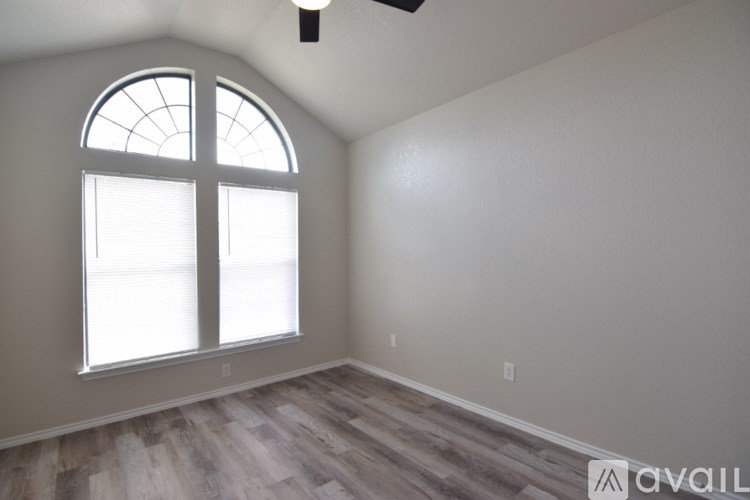 A room with a large window and wooden flooring.