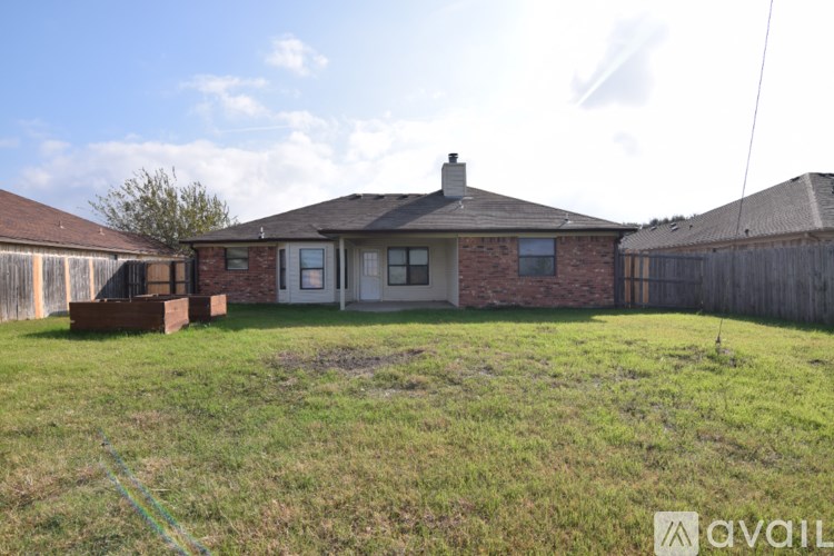 A house with a brown roof and a white door is surrounded by a grassy yard.