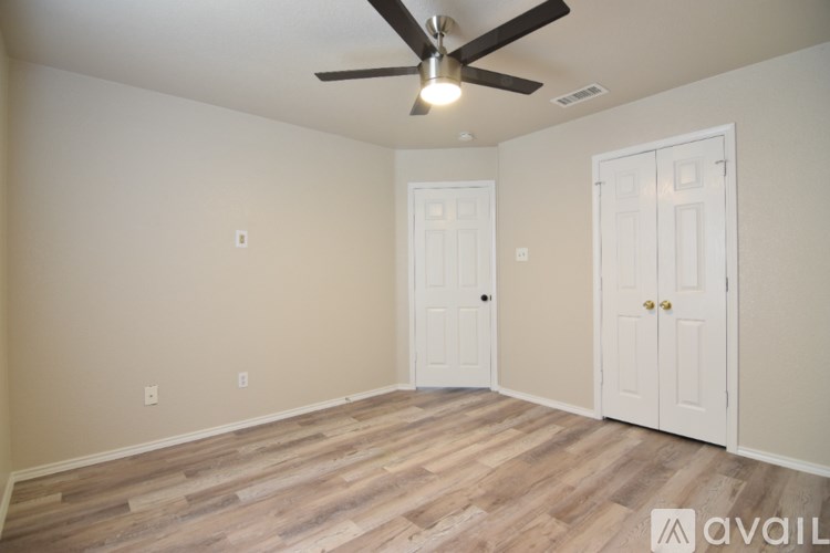 A room with a ceiling fan and two doors.