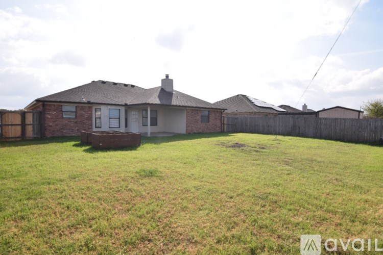 A house with a brown roof and a white door is surrounded by a wooden fence.