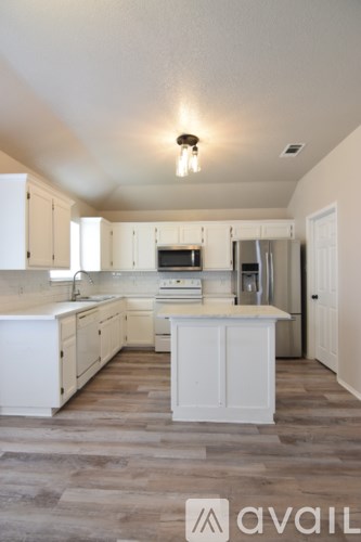 A kitchen with white cabinets and a wooden floor.