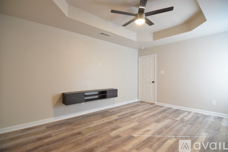 A room with a ceiling fan and a wooden floor.