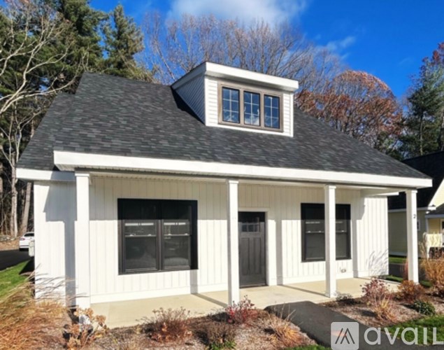 A small white house with a black roof and a window on the upper floor.