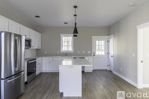 A kitchen with white cabinets and a white island.