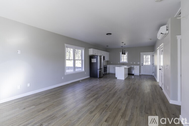 A spacious room with wooden flooring and white walls.
