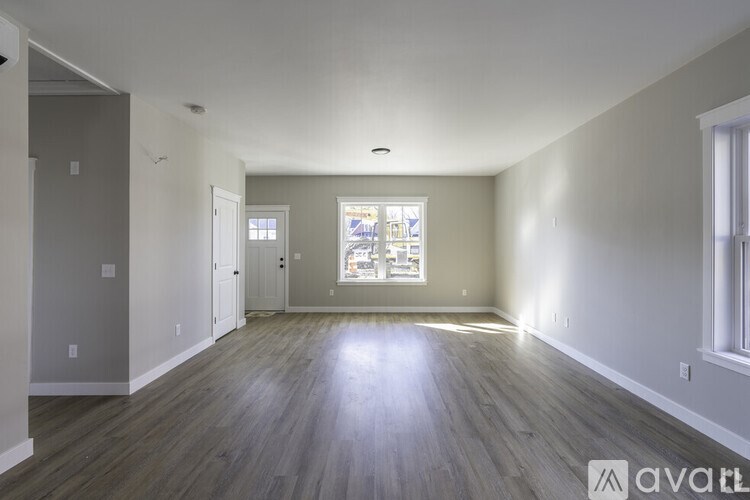 A spacious room with wooden floors and a window showing a view of a city.
