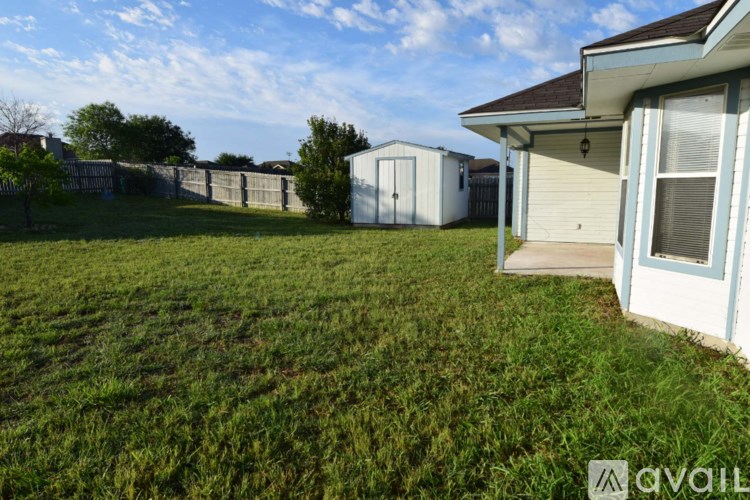 A grassy yard with a house and a storage unit.