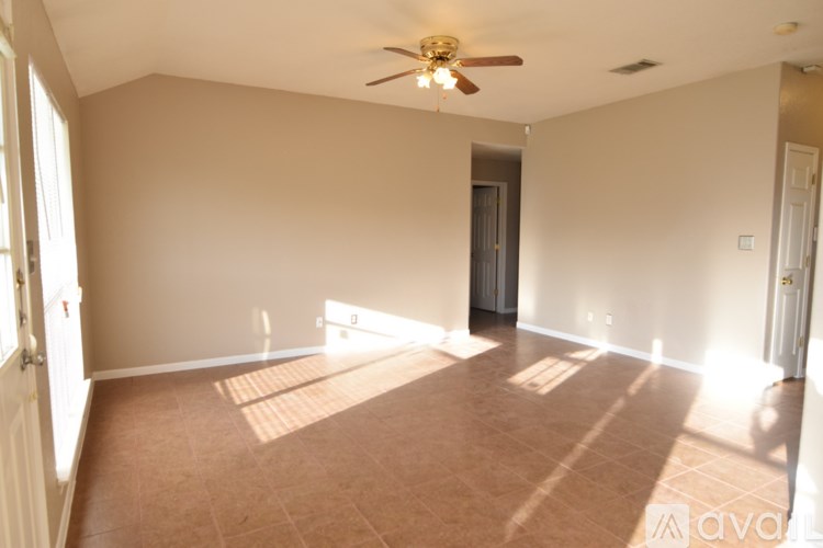 A room with a ceiling fan and brown tiled floor.