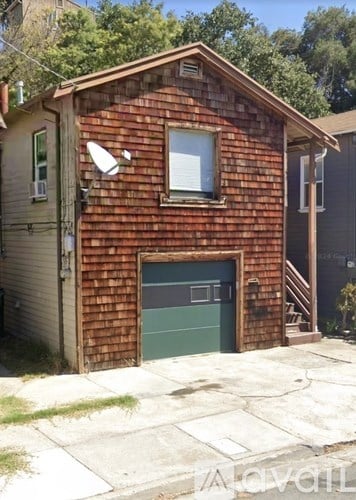 A small red brick house with a green garage door.