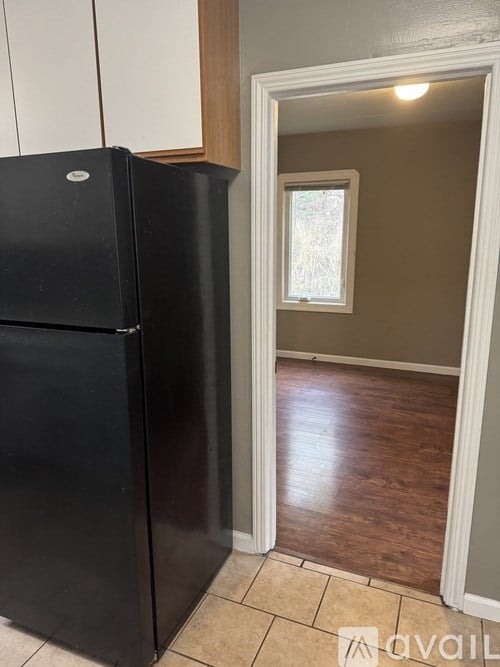 A black refrigerator is in a kitchen with a window.