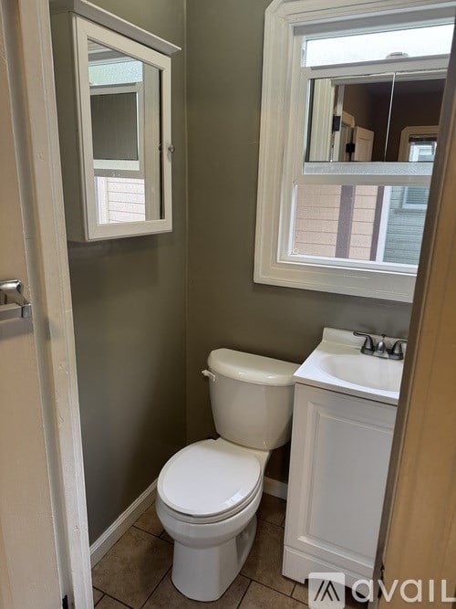 A white toilet sits in a bathroom next to a sink.