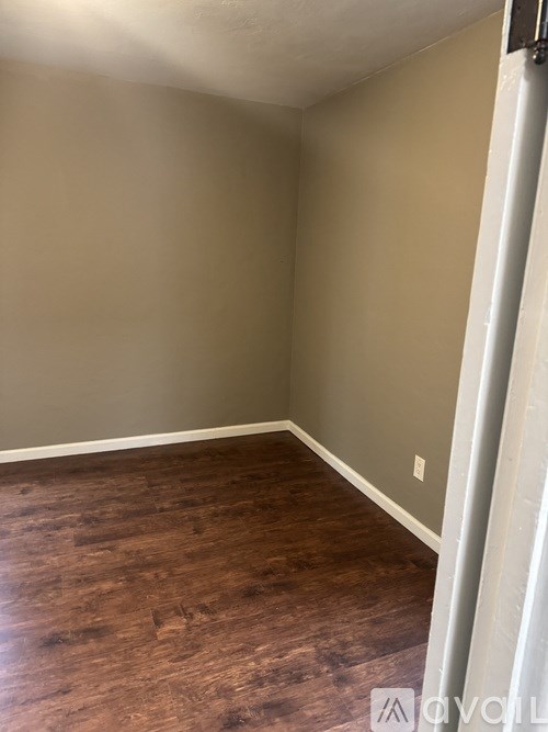 A room with wooden flooring and a white door.