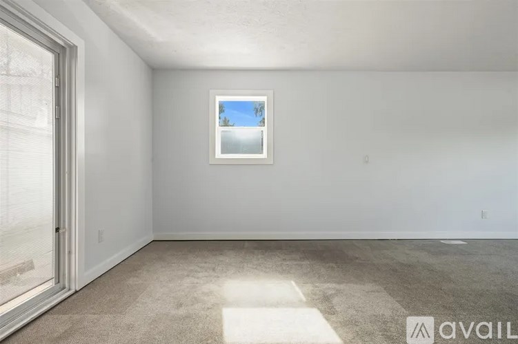 A room with a window and a painting on the wall.