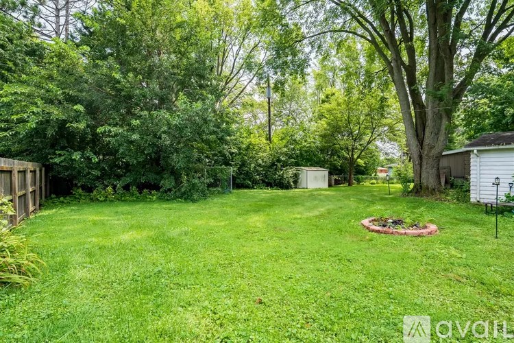 A backyard with a green lawn and trees.