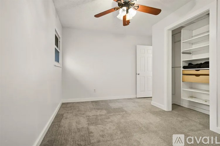A room with a ceiling fan and a closet with shelves.