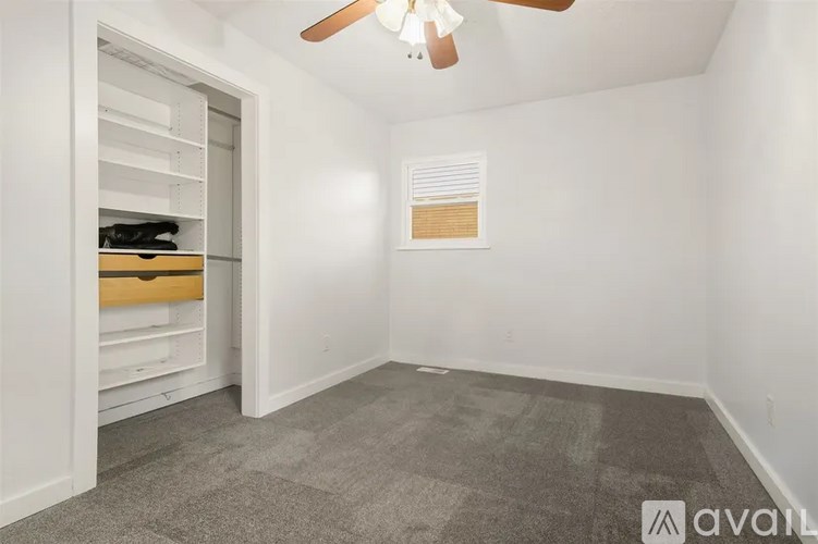 A room with a ceiling fan and a closet with shelves.