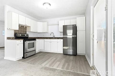 A kitchen with white cabinets and a stainless steel refrigerator.